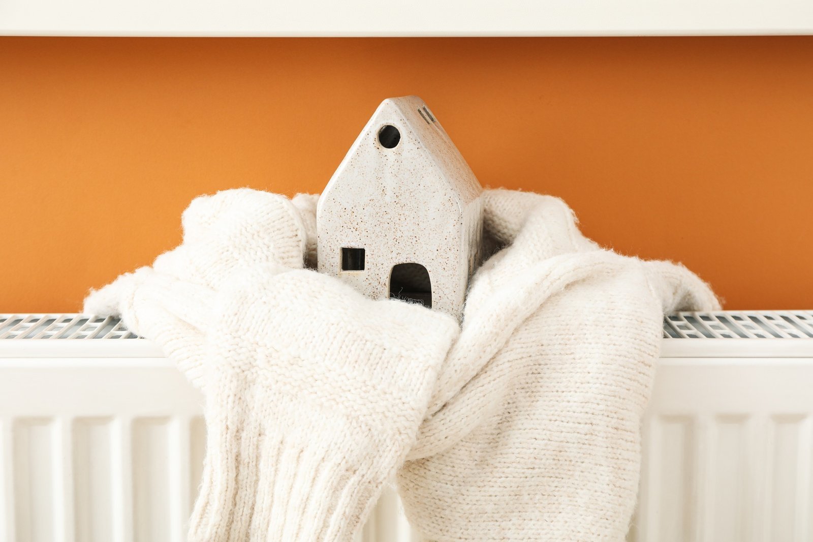 Cozy knit house ornament resting on a warm home radiator
